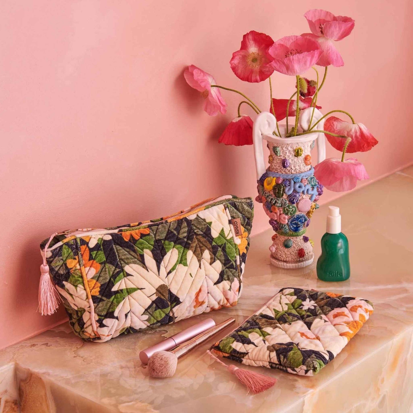 The Dreamy Floral Velvet Toiletry Bag from Kip & Co features printed quilted velvet with wild garden florals in shades of pink, orange, cream and white with hints of greenery on a black base with feature pink zip tassel.